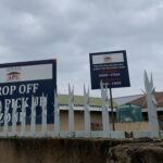 Lekazi Primary School entrance with drop-off and pick-up zone sign and gate opening times displayed